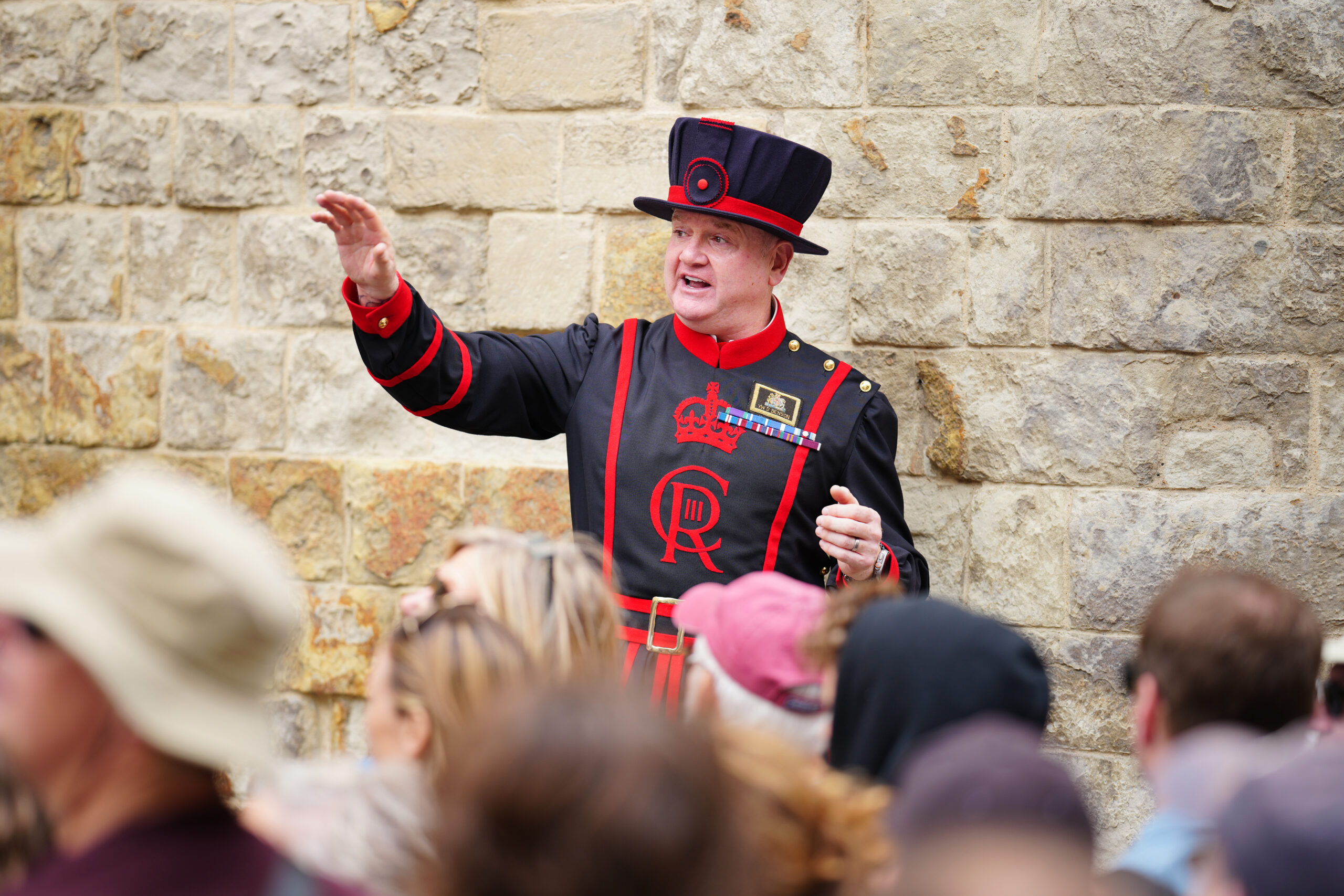 A Beefeater directing a tour group at the Tower of London, England.
